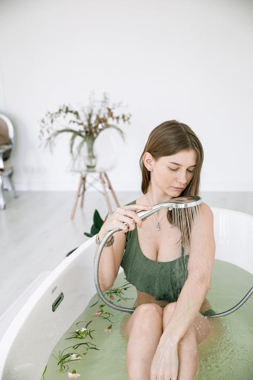 woman bathing in low water pressure from a showerhead