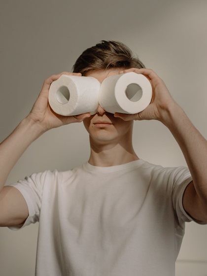 a person covering his eyes with toilet paper rolls
