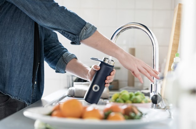 A person filling a water bottle in the kitchen