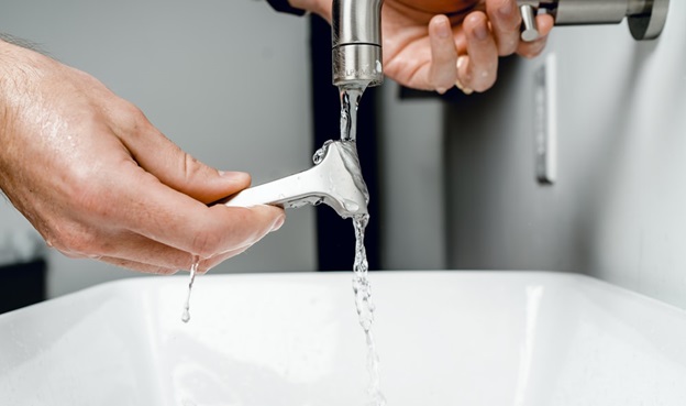 A man rinsing his shaving stick with low-pressure water