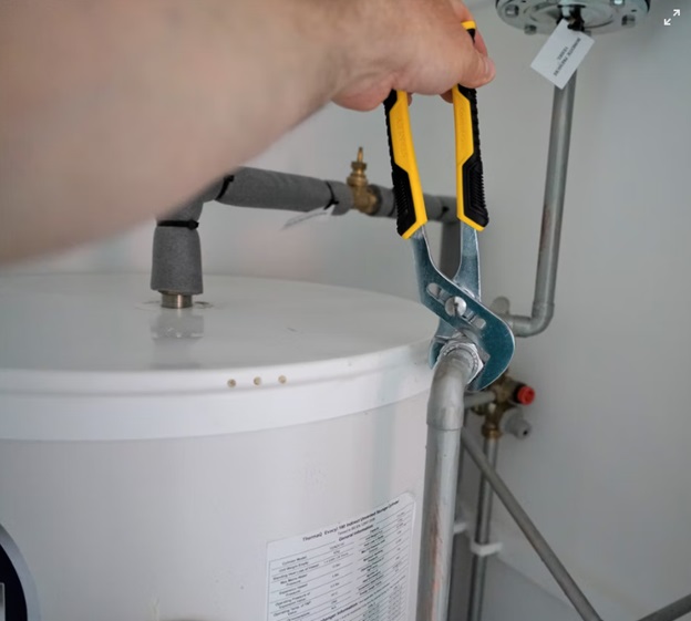 A plumber repairing the water heater with pliers
