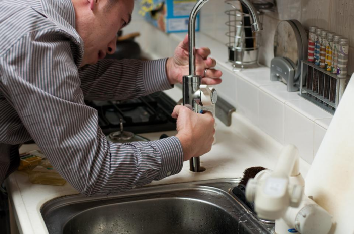 A plumber in Rockwall, TX, examining the heating system